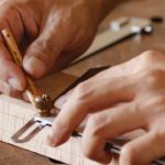 DIY Workshops - From above of crop unrecognizable tattooed male carpenter measuring wooden plank while creating new object in workshop