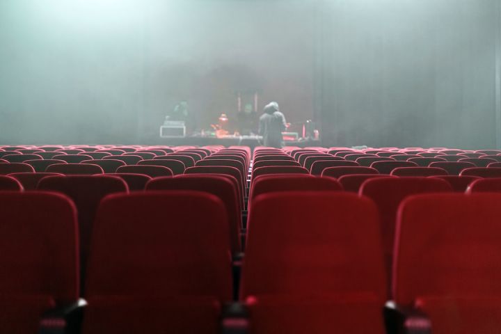 Theaters - people sitting on red chairs watching a band performing on stage