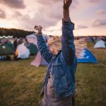 Outdoor Festival - a woman raising her arms in the air in front of tents