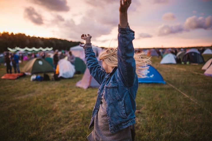 Outdoor Festival - a woman raising her arms in the air in front of tents