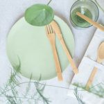 Eco-friendly - a green plate with wooden utensils on it