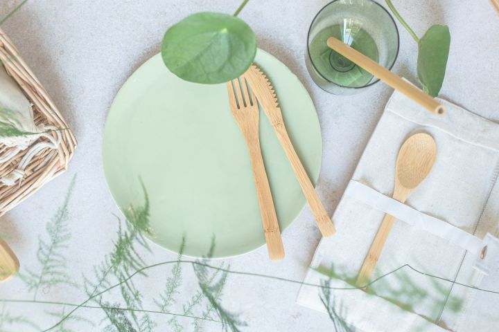 Eco-friendly - a green plate with wooden utensils on it