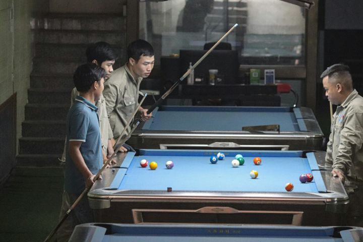 Chill Zone - a group of men standing around a pool table