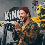 Comedian - man in red knit cap and yellow and black plaid dress shirt holding microphone
